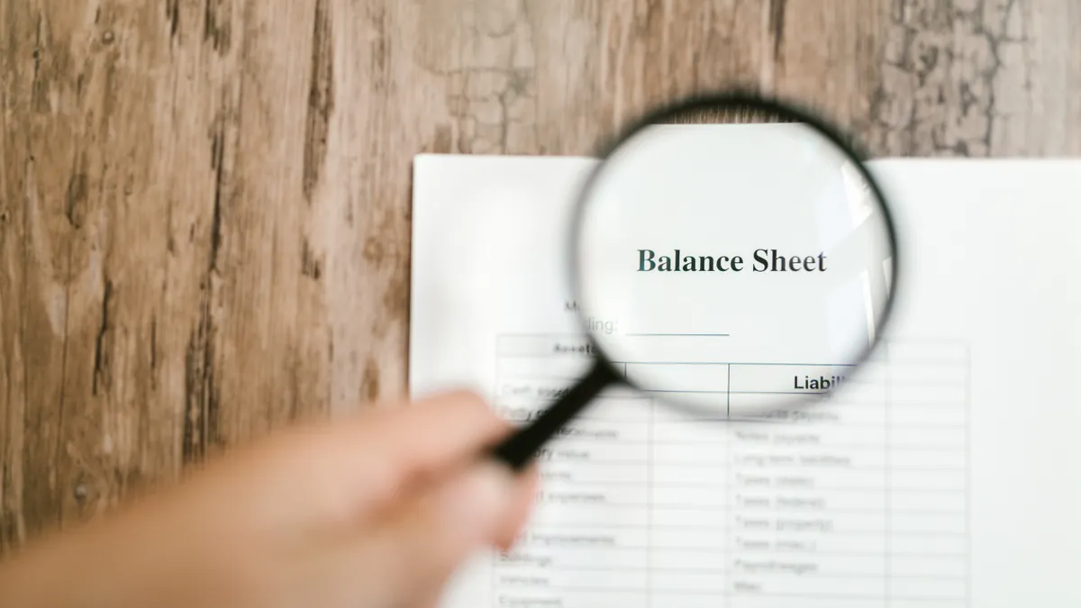 Magnifying glass over a balance sheet document
